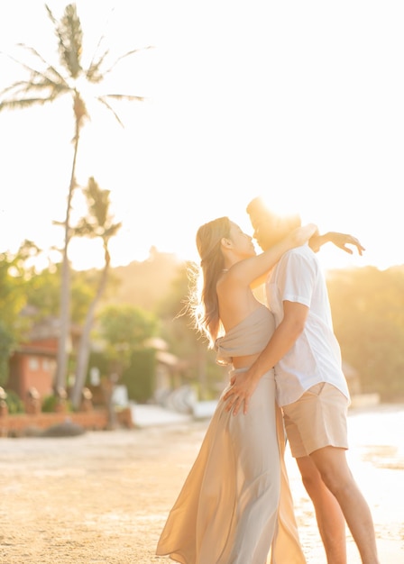 La coppia si abbraccia e si guarda sulla spiaggia al momento romantico del tramonto