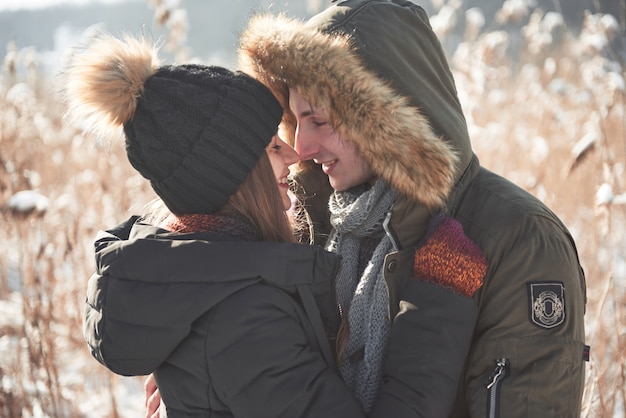 La coppia si diverte e ride. bacio. Giovani coppie dei pantaloni a vita bassa che si abbracciano nel parco di inverno. Storia d'amore invernale, una bellissima giovane coppia elegante. Moda invernale con fidanzato e fidanzata