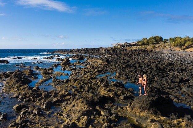 La coppia si trova su formazioni rocciose ruvide vicino all'oceano sull'isola di Tenerife, Isole Canarie, Tenerife, Spagna