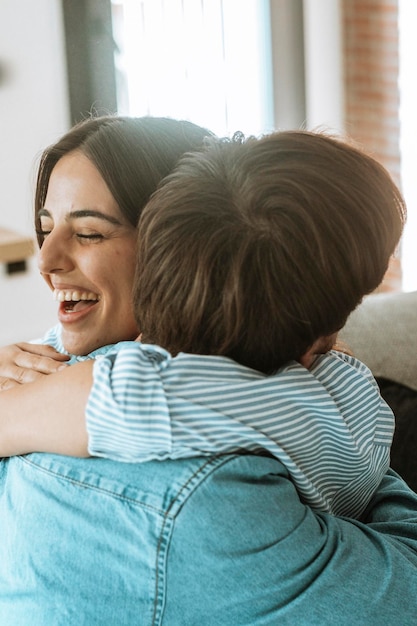 La coppia sorridente seduta sul divano a casa abbracciandosi felice concetto di amore e felicità l'uomo e la donna si abbracciano e sorridono con felicità realizzazione e gioia di relazione le persone pianificano la vita