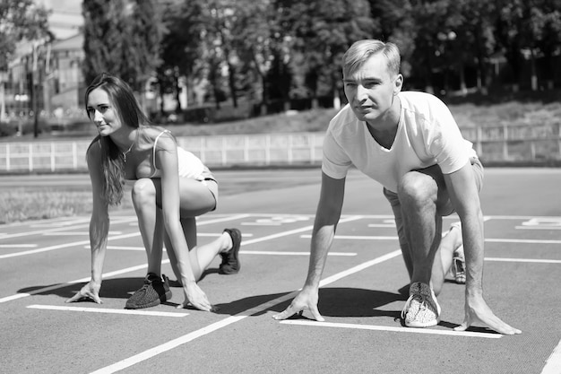 La coppia sportiva inizia la competizione correndo all'arena pista soleggiata estate all'aperto
