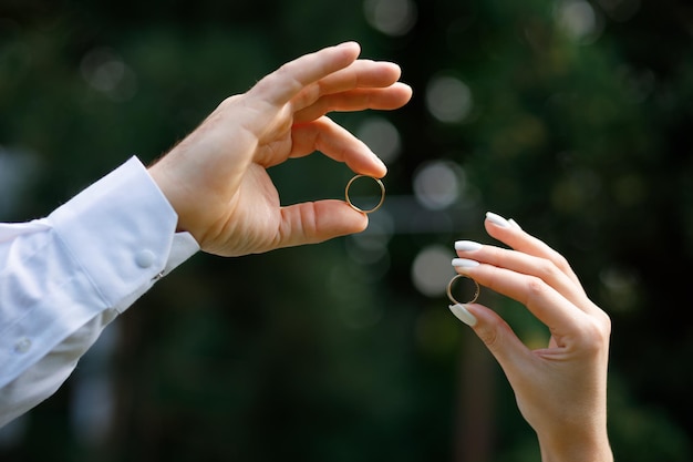 La coppia tiene in mano le fedi nuziali d'oro dopo il matrimonio e si ama