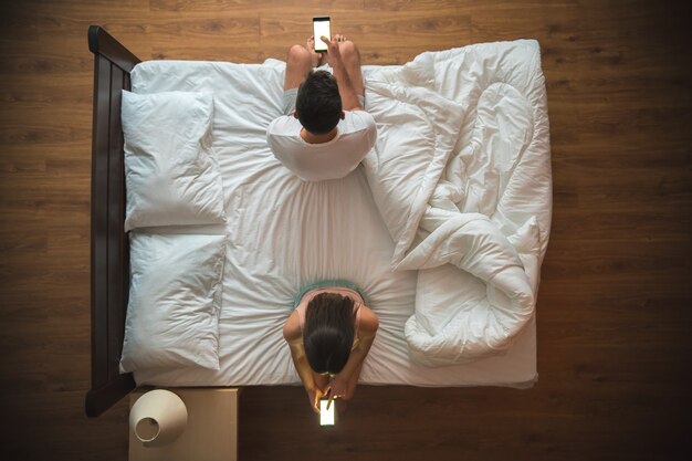 La coppia tiene uno smartphone sul letto. vista dall'alto