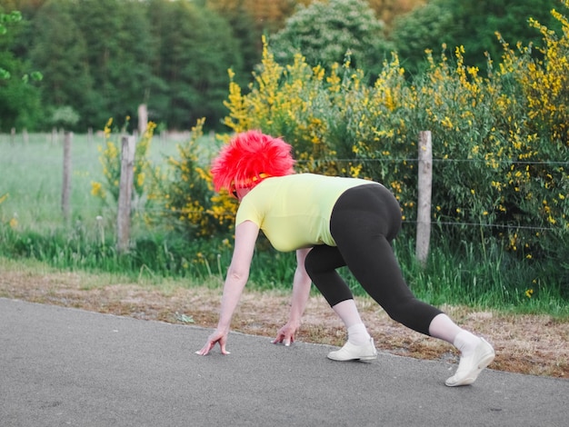 La corridore caucasica con una parrucca bandiera belga si prepara a correre una divertente maratona