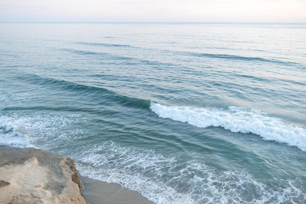 La costa dell'oceano è bagnata da un'onda. Spruzzi d'acqua. Riva sabbiosa al tramonto