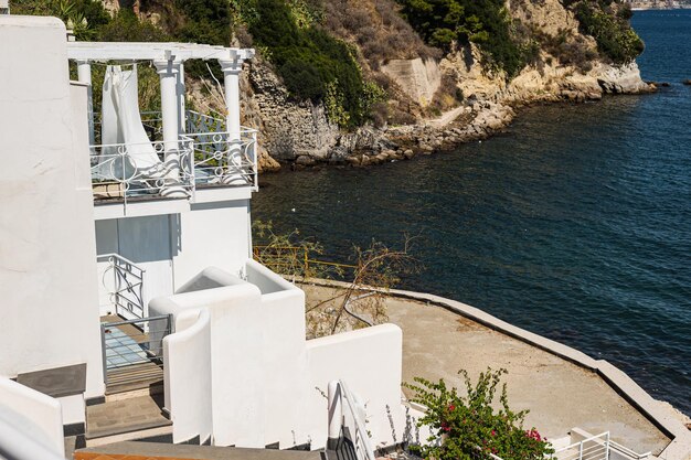 La costa rocciosa del sud Italia la città di Baia La terrazza estiva dell'hotel ristorante con una magnifica vista Mare calmo e bellissimo panorama del Mar Tirreno Vacanze europee