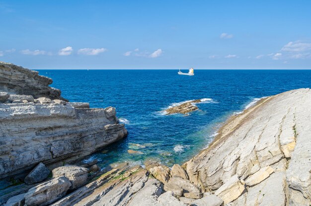 La costa rocciosa verde di Santander con le barche sullo sfondo