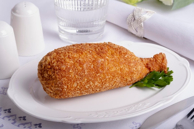 la costoletta di petto di pollo giace su un piatto bianco su un tavolo da pranzo