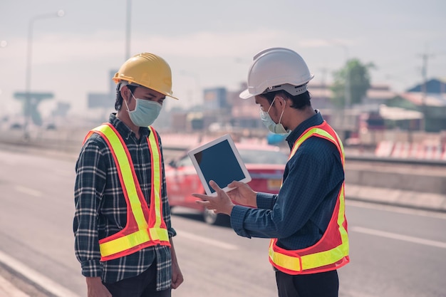 La costruzione di ingegneri asiatici è un lavoratore dipendente che lavora con un casco di controllo di sicurezza in loco