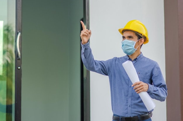 La costruzione di ingegneri asiatici è un lavoratore dipendente che lavora con un casco di controllo di sicurezza in loco