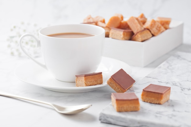 La crostata al caramello e al biscotto morde il dessert sul bordo di marmo e sulla tazza di caffè