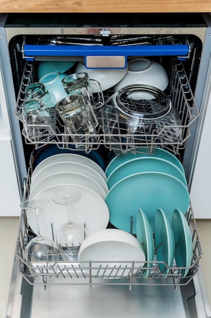 La cucina bianca e la lavastoviglie aperta con piatti puliti