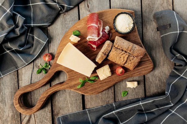 La cucina italiana concetto piatto laici. Tagliere, pezzi di parmigiano, formaggio grattugiato in ciotola nera