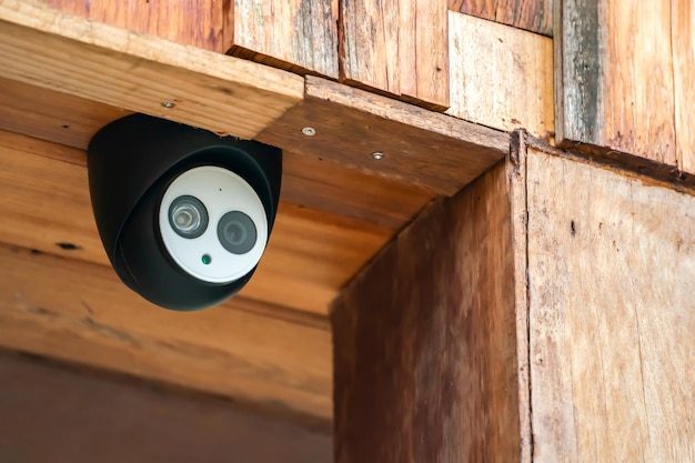 La custodia nera della mini telecamera CCTV da vicino è installata sull'edificio del soffitto in legno