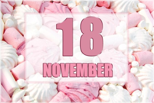 La data del calendario sullo sfondo dei marshmallow bianchi e rosa 18 novembre è il diciottesimo giorno del mese