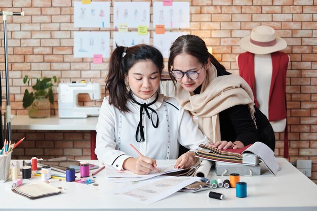 La designer asiatica e la sarta adolescente lavorano con tessuti colorati e filati da cucire