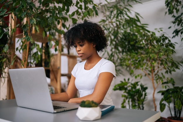 La designer libera professionista afroamericana che cerca e crea nuove idee fresche pensa al piano aziendale che lavora a distanza sul laptop