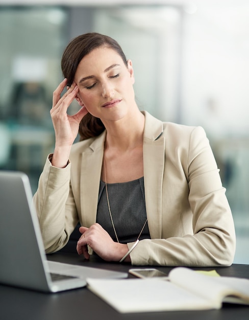 La dolorosa realtà del burnout professionale Inquadratura di una donna d'affari che soffre di mal di testa alla scrivania dell'ufficio