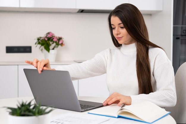 La donna abbastanza giovane e intelligente apre il laptop per studiare online a casa