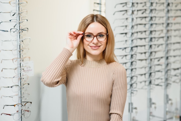 La donna abbastanza giovane sta scegliendo nuovi occhiali al negozio di ottica