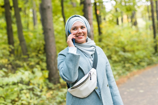 La donna abbastanza musulmana parla al telefono al parco.