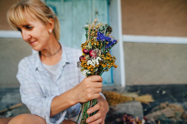 La donna adulta crea un mazzo di bei fiori secchi nel paese