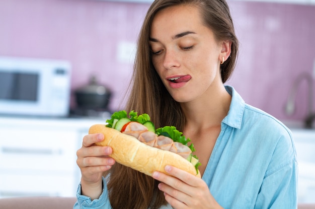 La donna affamata di cibo mangia il panino casalingo