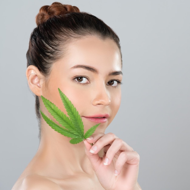 La donna affascinante del primo piano tiene la foglia verde come concetto di bellezza della cannabis