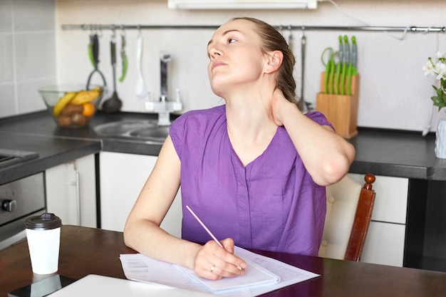 La donna affaticata si sente stanca di stare seduta a lungo al tavolo della cucina