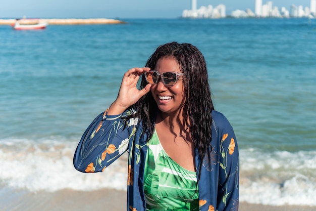 La donna africana gode del tempo libero all'aperto vicino all'oceano in spiaggia. Turista sorridente felice nei tropici.