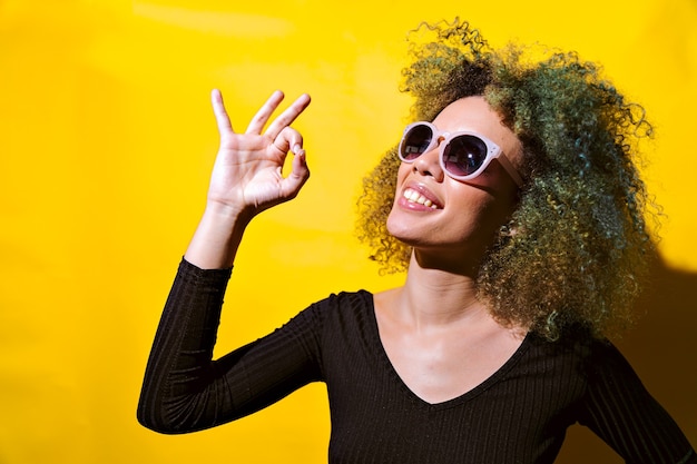 La donna afro indica OK su sfondo giallo