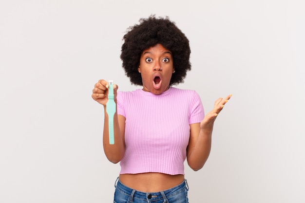 La donna afro si sente estremamente scioccata e sorpresa, ansiosa e in preda al panico, con un concetto di orologio dall'aspetto stressato e inorridito