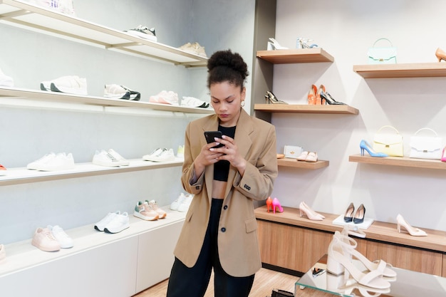 La donna afroamericana digita sul suo telefono durante lo shopping