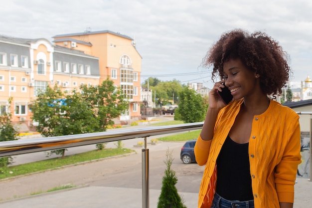 La donna afroamericana felice che parla al telefono in strada