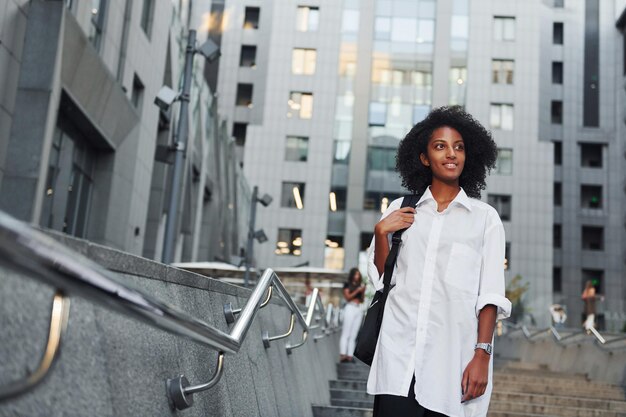 La donna afroamericana in bei vestiti è all'aperto in città durante il giorno