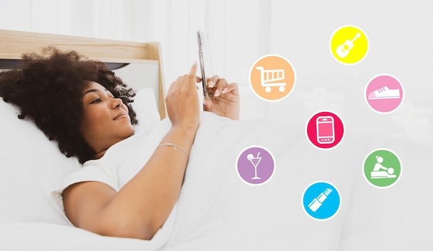 La donna afroamericana si sveglia e inizia a giocare sul suo smartphone preferito ordinando online.