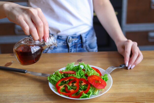 la donna aggiunge olio all'insalata, l'uso di olio d'oliva nella dieta