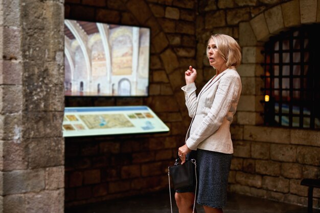 La donna al museo utilizza la guida elettronica del monitor touchscreen