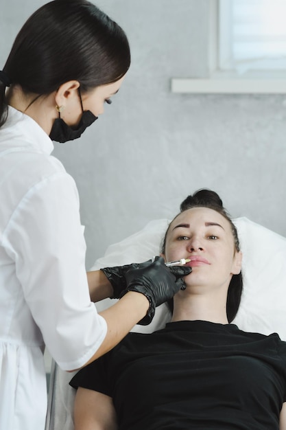 la donna allarga le labbra con acido ialuronico da un cosmetologo Cosmetologia per iniezione Filler per labbra