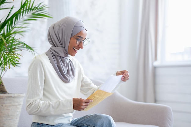 La donna allegra a casa ha ricevuto una lettera di notifica per posta con buone notizie la donna musulmana in hijab è felice