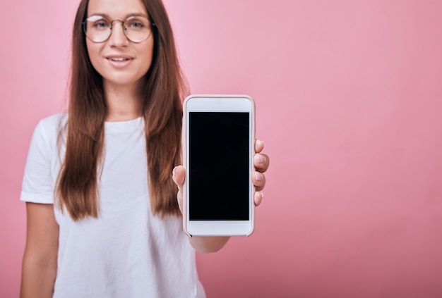 La donna allegra mostra l'esposizione del telefono proprio nel telaio