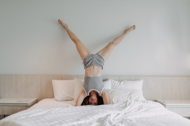 La donna allegra sta facendo una posa a testa in giù sul letto