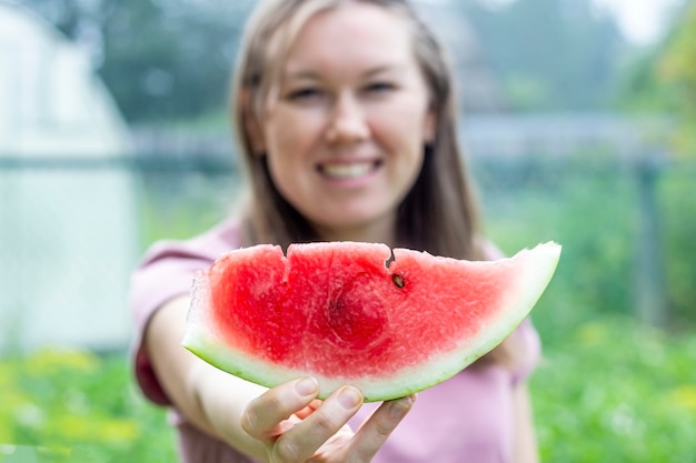 La donna allegra tiene una fetta di anguria davanti a lei. Concetto di vacanza estiva. Mangiare sano. concetto di corretta alimentazione, alimenti biologici e vegetariani.