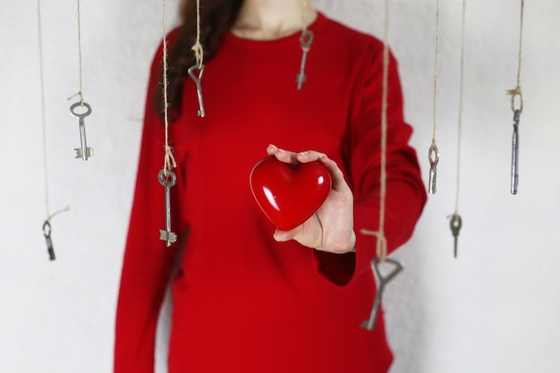 La donna allunga la mano con una forma di cuore rosso circondato da un filo chiave