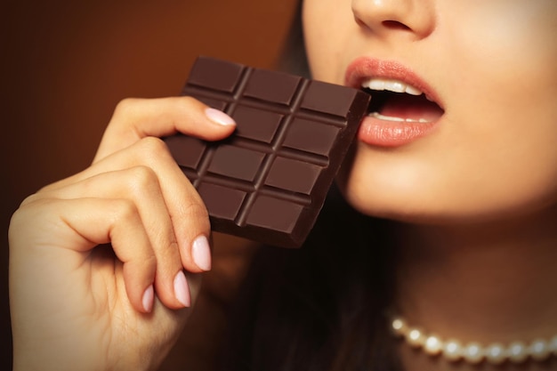 La donna amante del cioccolato morde il bar per godersi il sapore da vicino.