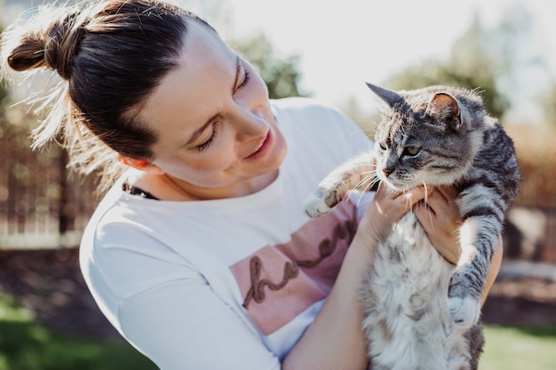 La donna ammira il suo animale domestico, tenendolo tra le braccia in una giornata di sole