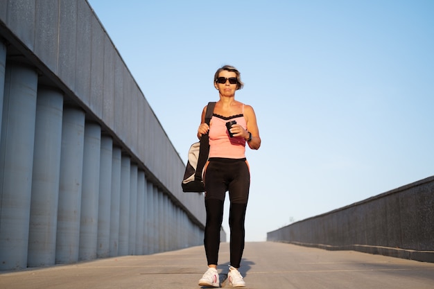 La donna anziana attiva va in allenamento fitness in città