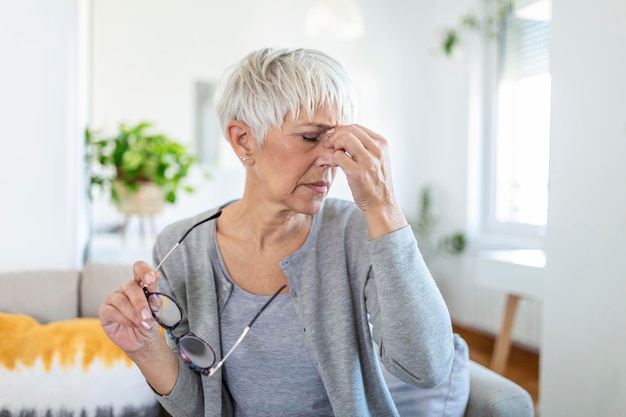 La donna anziana con gli occhiali si strofina gli occhi, soffre di occhi stanchi, concetto di malattie oculari