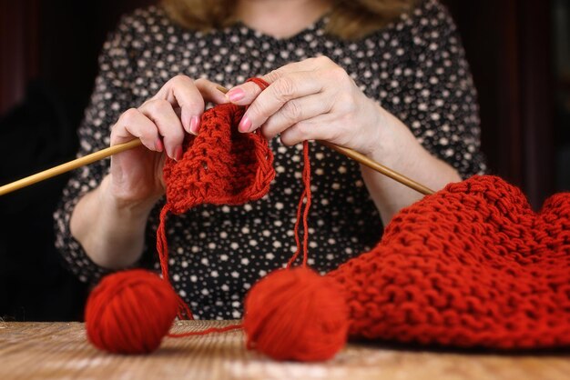 La donna anziana è impegnata a lavorare a maglia maglioni caldi per i suoi nipoti