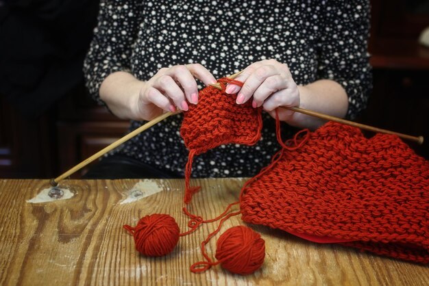 La donna anziana è impegnata a lavorare a maglia maglioni caldi per i suoi nipoti